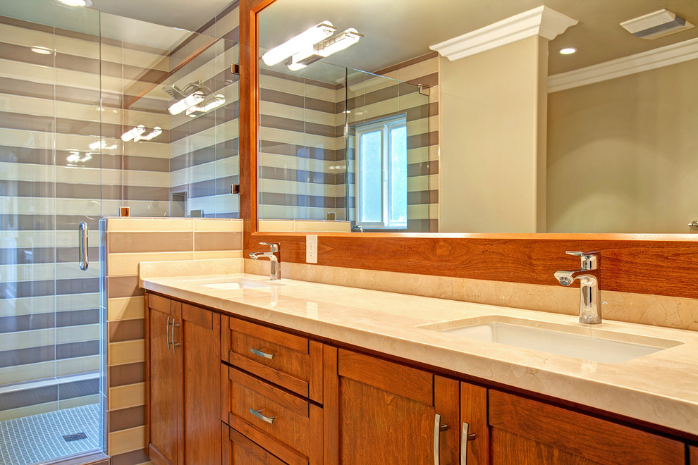 Exemple d'une salle de bain chic en bois brun de taille moyenne pour enfant avec un lavabo encastré, un placard à porte shaker, un plan de toilette en calcaire, une baignoire posée, une douche ouverte, un carrelage gris, mosaïque, un mur gris et un sol en carrelage de céramique.