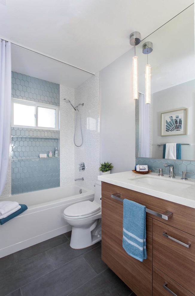 Design ideas for a medium sized traditional family bathroom in San Diego with shaker cabinets, brown cabinets, an alcove bath, a shower/bath combination, a two-piece toilet, blue tiles, glass tiles, red walls, porcelain flooring, a submerged sink, engineered stone worktops, grey floors, a shower curtain and white worktops.
