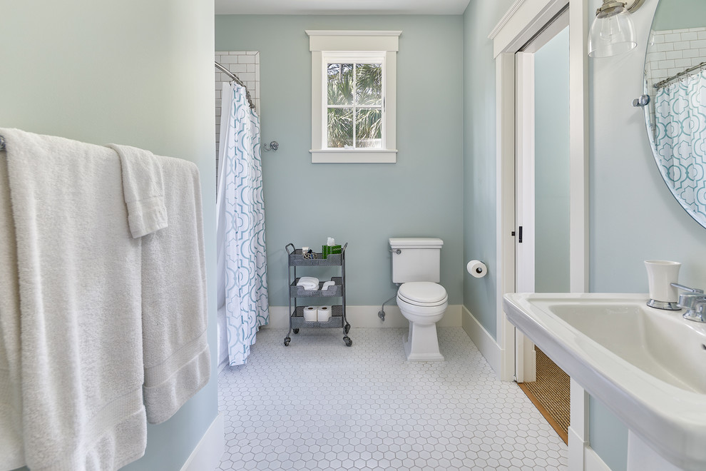 チャールストンにある高級な広いビーチスタイルのおしゃれな子供用バスルーム (白いキャビネット、ドロップイン型浴槽、シャワー付き浴槽	、壁掛け式トイレ、モザイクタイル、壁付け型シンク、白い床、シャワーカーテン、青い壁) の写真