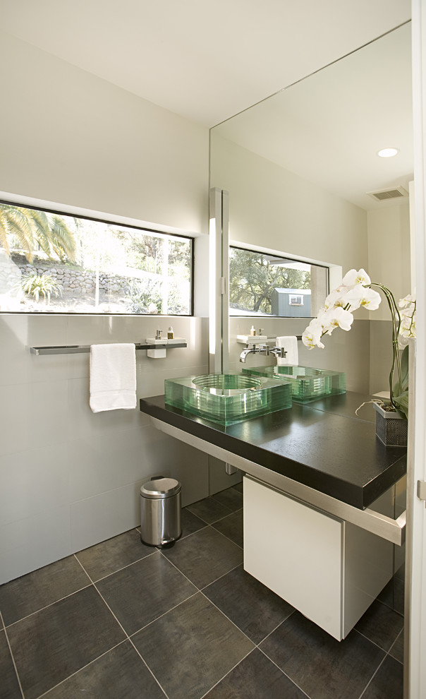Пример оригинального дизайна: маленькая ванная комната в современном стиле с настольной раковиной, серой плиткой, каменной плиткой, плоскими фасадами, белыми фасадами, белыми стенами и полом из керамической плитки для на участке и в саду