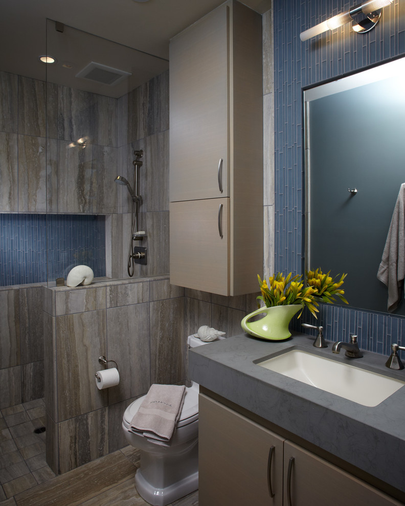 Esempio di una piccola stanza da bagno costiera con lavabo sottopiano, ante lisce, ante in legno chiaro, doccia ad angolo, WC a due pezzi, piastrelle blu, piastrelle di vetro e pareti grigie