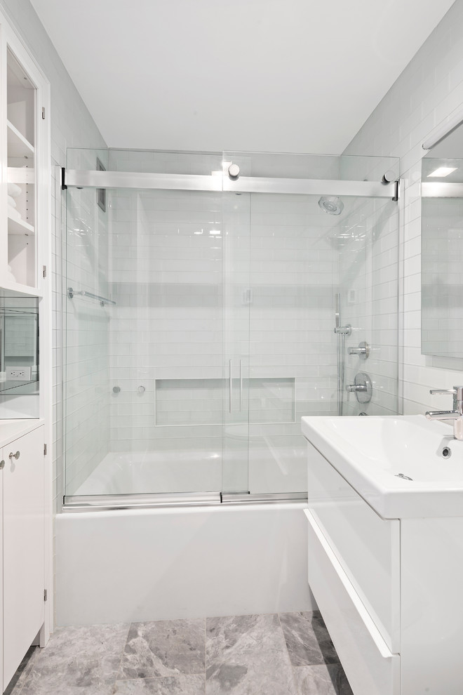 Diseño de cuarto de baño moderno pequeño con armarios tipo vitrina, puertas de armario blancas, sanitario de una pieza, baldosas y/o azulejos blancos, paredes blancas, suelo de mármol, aseo y ducha y lavabo suspendido