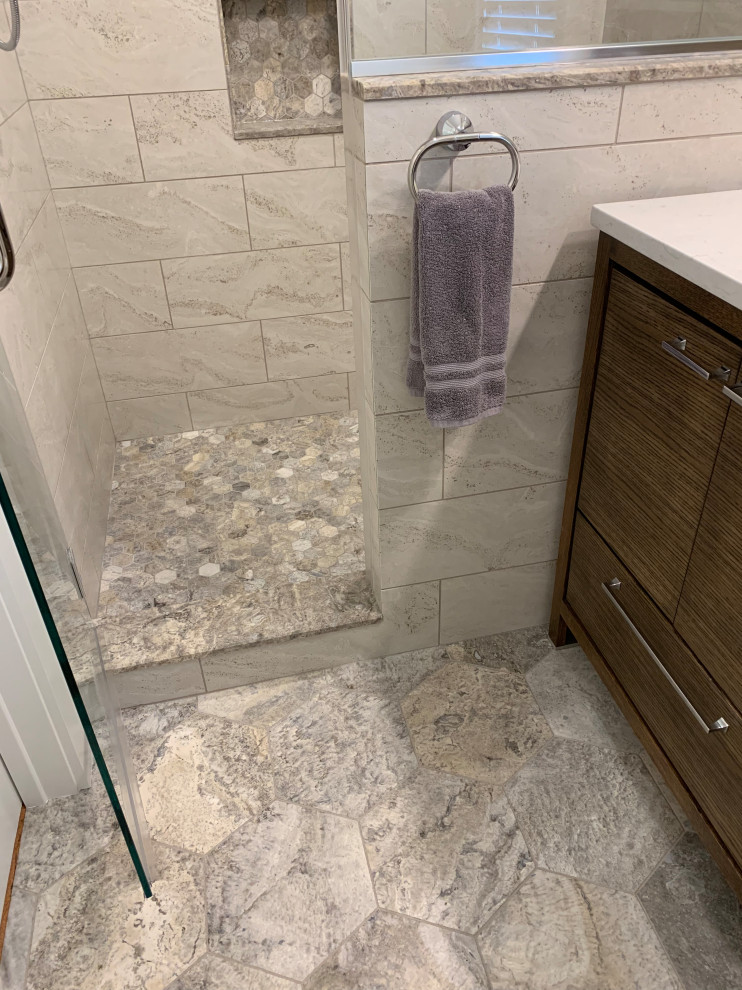 Inspiration for a medium sized modern bathroom in Milwaukee with flat-panel cabinets, medium wood cabinets, a walk-in shower, a two-piece toilet, grey tiles, limestone tiles, limestone flooring, a submerged sink, engineered stone worktops, grey floors, a hinged door and white worktops.