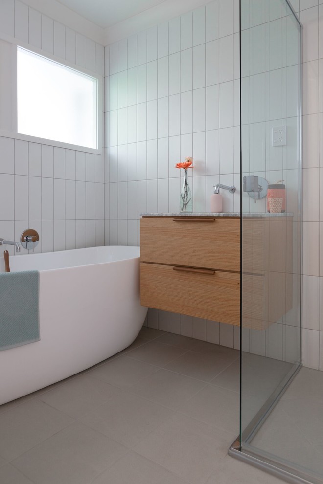 Inspiration för ett mellanstort funkis vit vitt badrum med dusch, med skåp i ljust trä, vita väggar, cementgolv, ett undermonterad handfat, marmorbänkskiva, beiget golv, möbel-liknande, ett fristående badkar, vit kakel och keramikplattor