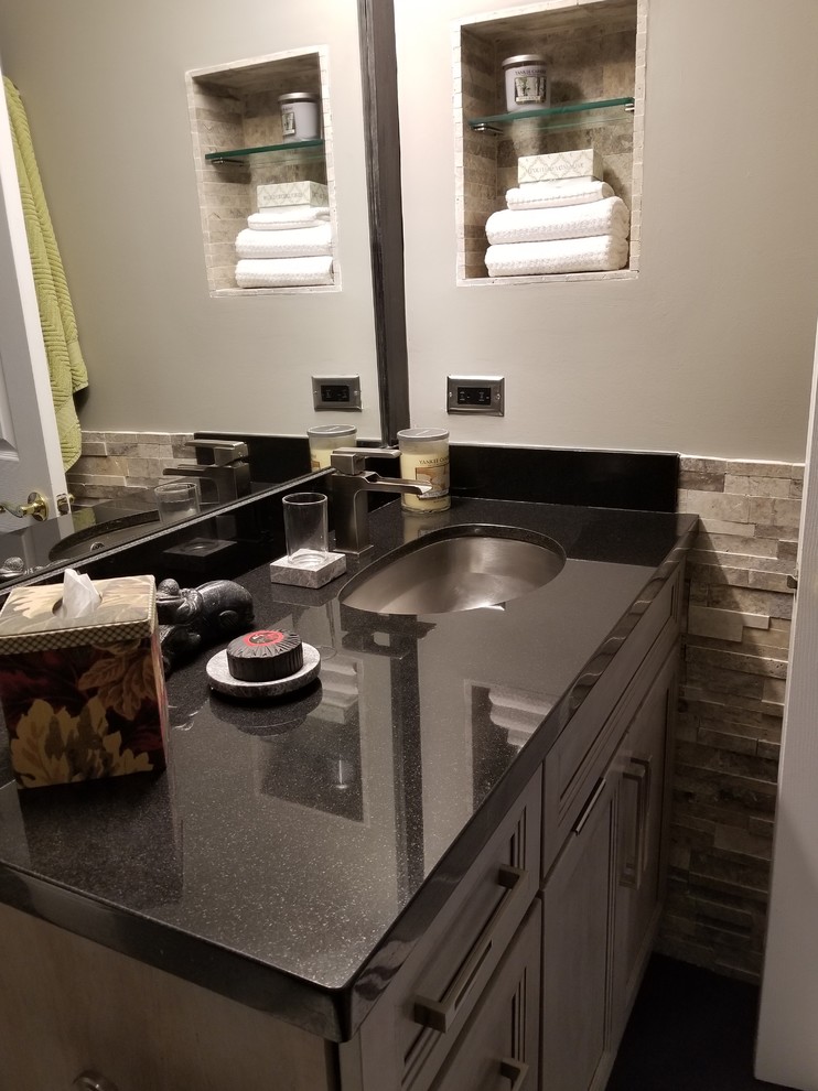 Photo of a medium sized traditional shower room bathroom in Miami with recessed-panel cabinets, grey cabinets, a one-piece toilet, grey tiles, stone tiles, grey walls, a submerged sink, granite worktops and black floors.