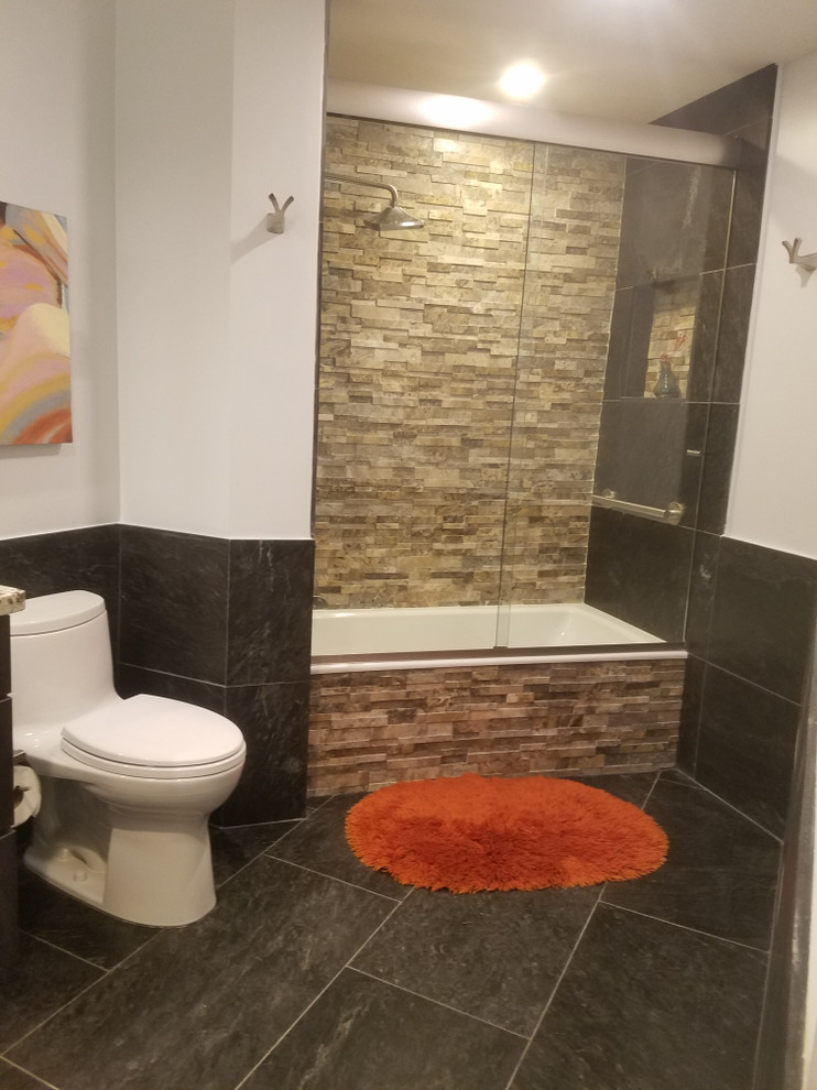 Example of a mid-sized transitional master black tile and stone tile slate floor and black floor bathroom design in Miami with shaker cabinets, gray cabinets, a one-piece toilet, gray walls, a vessel sink, granite countertops, a hinged shower door and white countertops