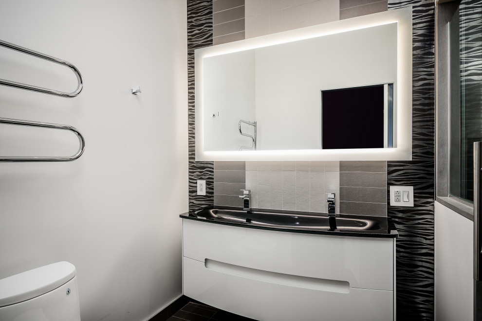 Inredning av ett modernt mellanstort svart svart en-suite badrum, med släta luckor, vita skåp, en dusch i en alkov, en toalettstol med hel cisternkåpa, flerfärgad kakel, porslinskakel, vita väggar, klinkergolv i porslin, bänkskiva i glas, grått golv och dusch med gångjärnsdörr