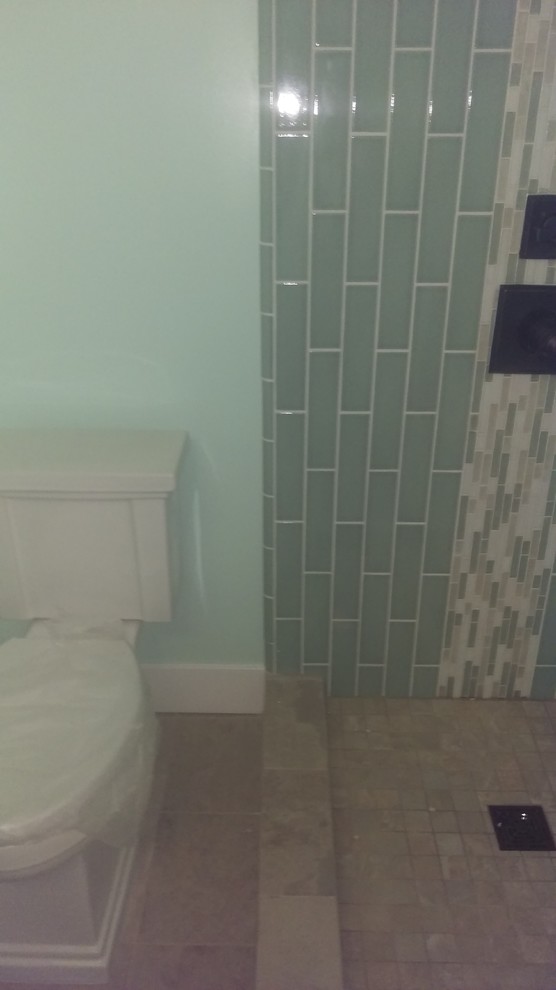 Inredning av ett amerikanskt litet badrum med dusch, med ett undermonterad handfat, skåp i shakerstil, skåp i mellenmörkt trä, bänkskiva i kvarts, en hörndusch, en toalettstol med hel cisternkåpa, flerfärgad kakel, glaskakel, gröna väggar och klinkergolv i porslin