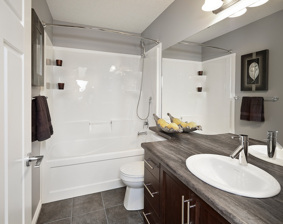 Amerikansk inredning av ett mellanstort badrum, med ett nedsänkt handfat, skåp i mörkt trä, laminatbänkskiva, en dusch/badkar-kombination och klinkergolv i keramik