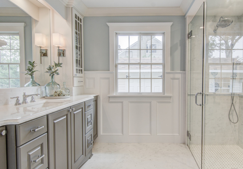 Photo of a large traditional family bathroom in Other with raised-panel cabinets, grey cabinets, a built-in shower, a two-piece toilet, white tiles, porcelain tiles, blue walls, marble flooring, a submerged sink, engineered stone worktops, white floors, a hinged door and white worktops.