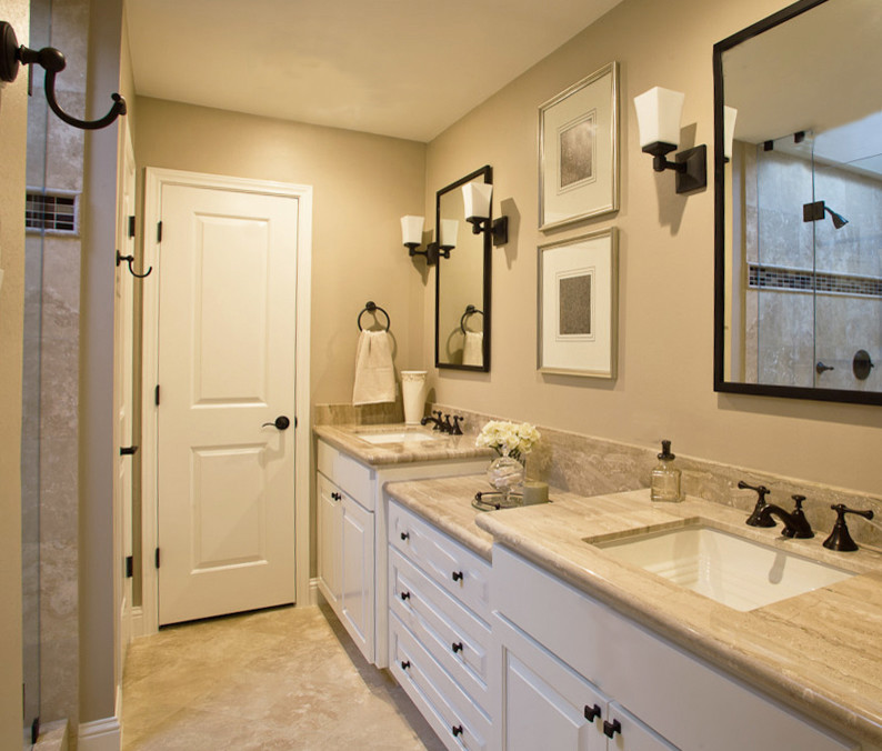 Cette image montre une petite salle de bain traditionnelle avec un placard avec porte à panneau surélevé, des portes de placard blanches, un carrelage beige, un carrelage de pierre, un mur beige, un sol en travertin et un lavabo encastré.