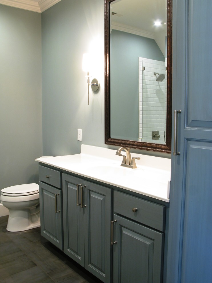 Inspiration for a medium sized contemporary family bathroom in Charlotte with a shower/bath combination, white tiles, metro tiles, blue walls, an integrated sink, blue cabinets, a built-in bath and a one-piece toilet.