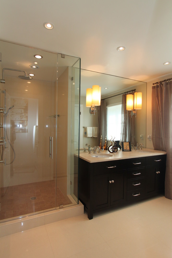 На фото: ванная комната: освещение в современном стиле с врезной раковиной, темными деревянными фасадами, душем в нише и бежевой плиткой