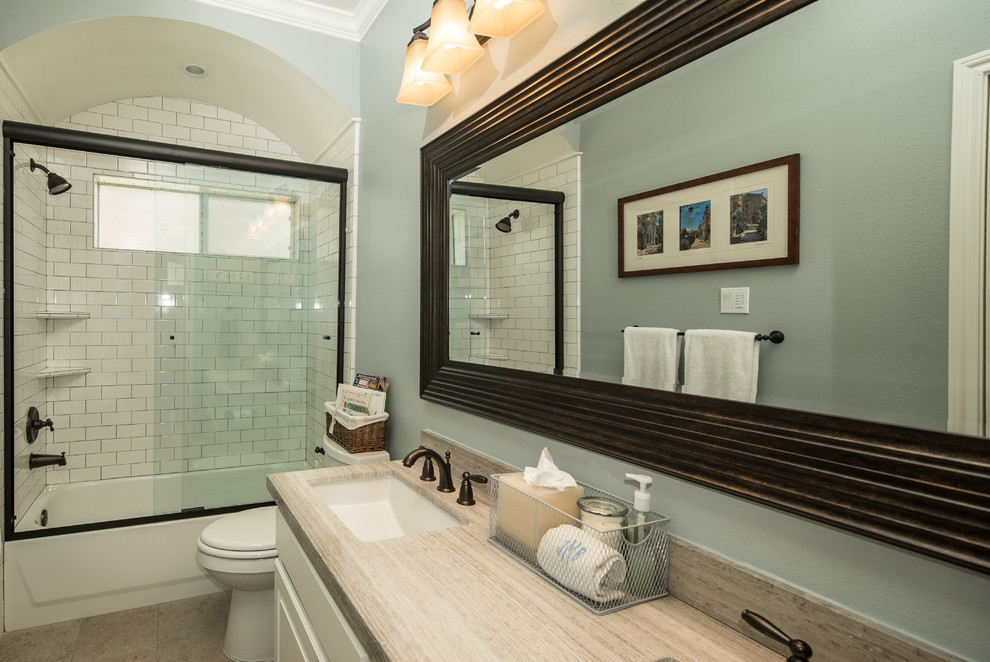 Design ideas for a medium sized traditional family bathroom in Houston with a submerged sink, flat-panel cabinets, white cabinets, limestone worktops, an alcove bath, an alcove shower, white tiles, metro tiles, blue walls and porcelain flooring.