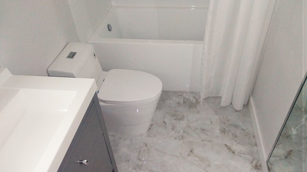 Inspiration pour une salle d'eau design de taille moyenne avec un placard à porte plane, des portes de placard grises, une baignoire en alcôve, un combiné douche/baignoire, WC à poser, un carrelage blanc, des carreaux de céramique, un mur gris, un sol en carrelage de porcelaine, une grande vasque, un plan de toilette en surface solide, un sol gris, une cabine de douche avec un rideau et un plan de toilette blanc.