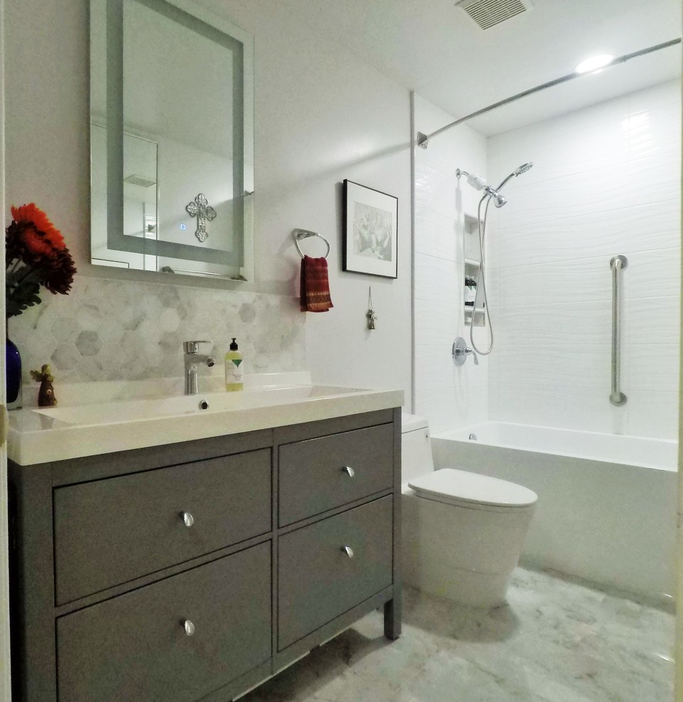 Стильный дизайн: ванная комната среднего размера в современном стиле с плоскими фасадами, серыми фасадами, ванной в нише, душем над ванной, унитазом-моноблоком, белой плиткой, керамической плиткой, серыми стенами, полом из керамогранита, душевой кабиной, раковиной с несколькими смесителями, столешницей из искусственного камня, серым полом, шторкой для ванной и белой столешницей - последний тренд