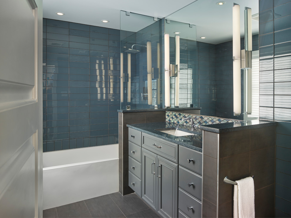 Idéer för att renovera ett mellanstort vintage blå blått badrum för barn, med luckor med infälld panel, grå skåp, ett badkar i en alkov, en dusch/badkar-kombination, en vägghängd toalettstol, blå kakel, glaskakel, blå väggar, klinkergolv i porslin, ett undermonterad handfat, bänkskiva i kvarts, grått golv och med dusch som är öppen