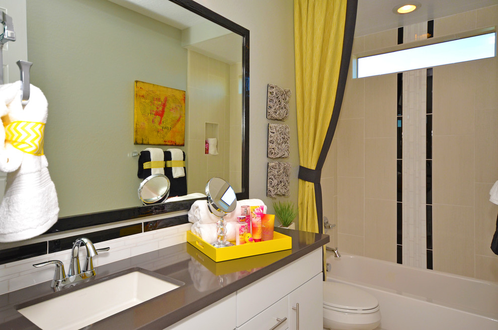 Example of a mid-sized trendy kids' beige tile and porcelain tile porcelain tile bathroom design in Phoenix with a drop-in sink, flat-panel cabinets, white cabinets, quartz countertops, a one-piece toilet and gray walls