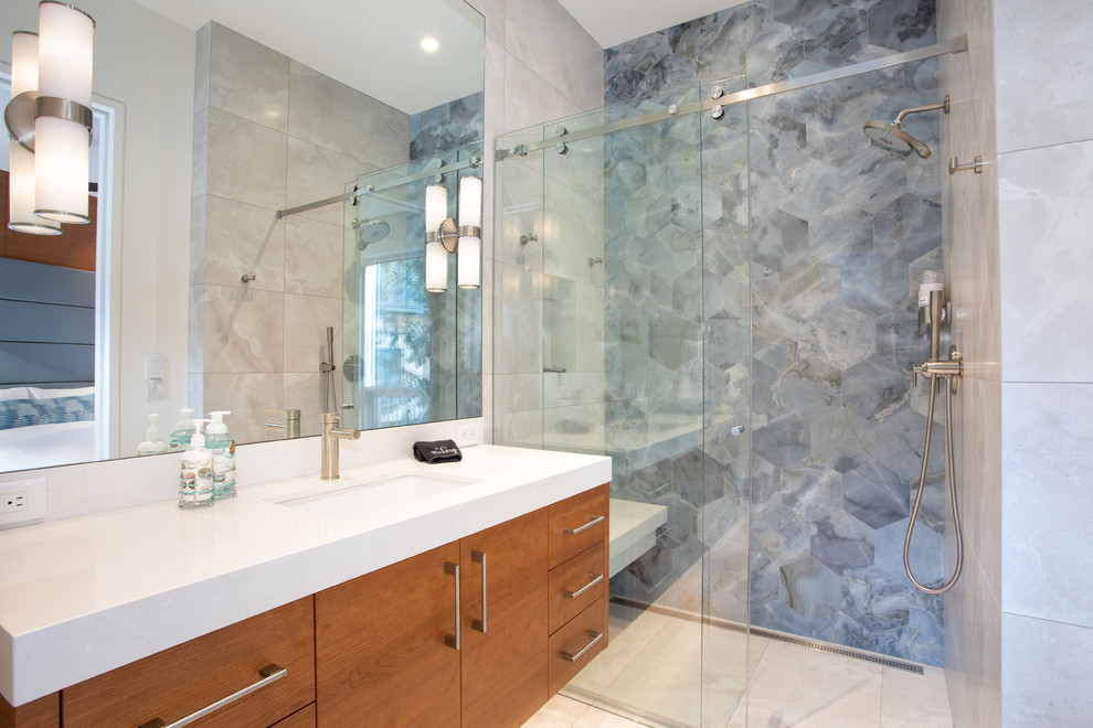 Modernes Duschbad mit flächenbündigen Schrankfronten, hellbraunen Holzschränken, bodengleicher Dusche, blauen Fliesen, Unterbauwaschbecken, beigem Boden, Schiebetür-Duschabtrennung und weißer Waschtischplatte in Vancouver