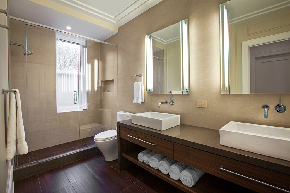 Photo of a large contemporary ensuite bathroom in Chicago with a vessel sink, flat-panel cabinets, medium wood cabinets, engineered stone worktops, a walk-in shower, a two-piece toilet, beige tiles, porcelain tiles, beige walls and porcelain flooring.