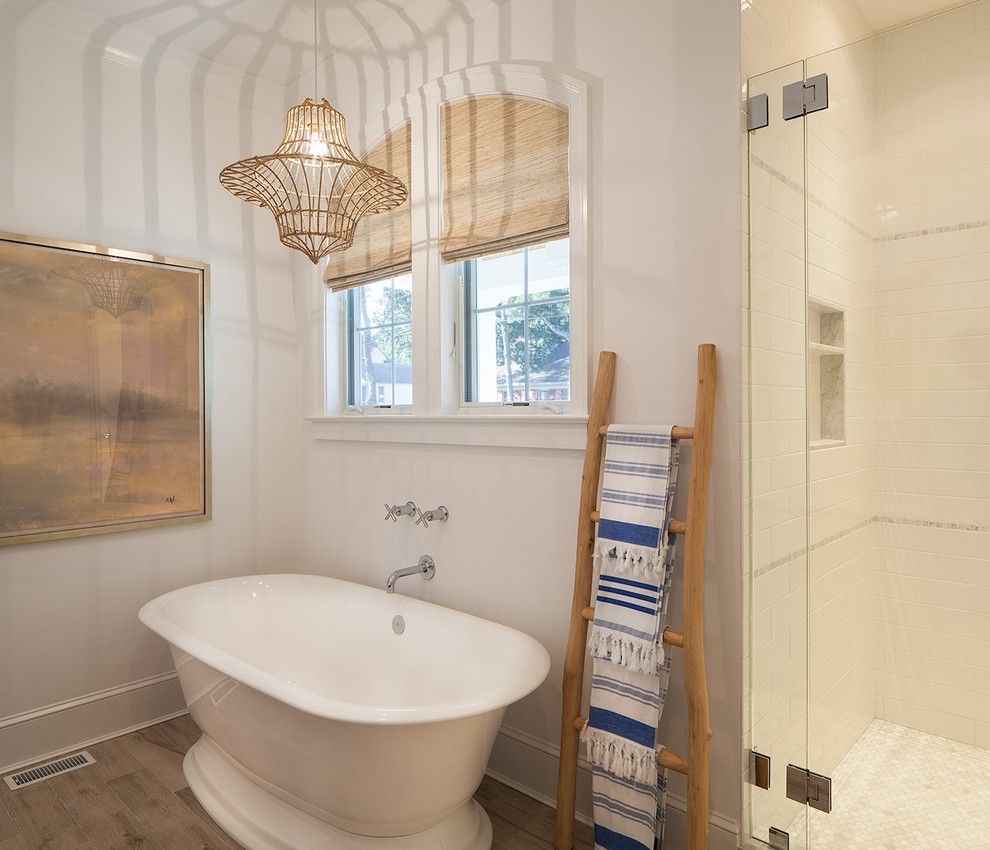 Photo of a coastal ensuite bathroom in New York with a freestanding bath, white tiles, metro tiles, white walls and a hinged door.