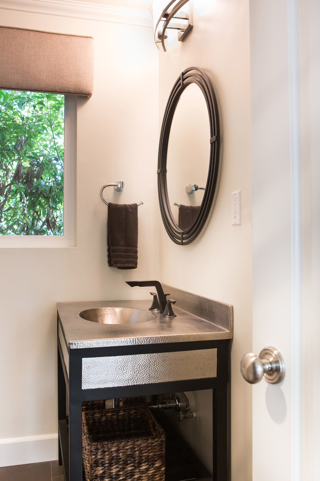 Foto på ett mellanstort vintage badrum med dusch, med ett integrerad handfat, möbel-liknande, svarta skåp, bänkskiva i rostfritt stål, en hörndusch, en toalettstol med separat cisternkåpa, grå kakel, porslinskakel, beige väggar och klinkergolv i porslin