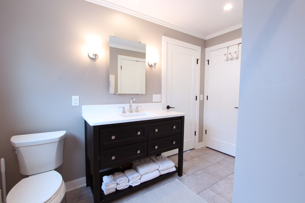 Inspiration for a medium sized classic family bathroom in Other with recessed-panel cabinets, black cabinets, an alcove bath, an alcove shower, a two-piece toilet, white tiles, porcelain tiles, grey walls, porcelain flooring, a submerged sink, engineered stone worktops, grey floors, a shower curtain and white worktops.