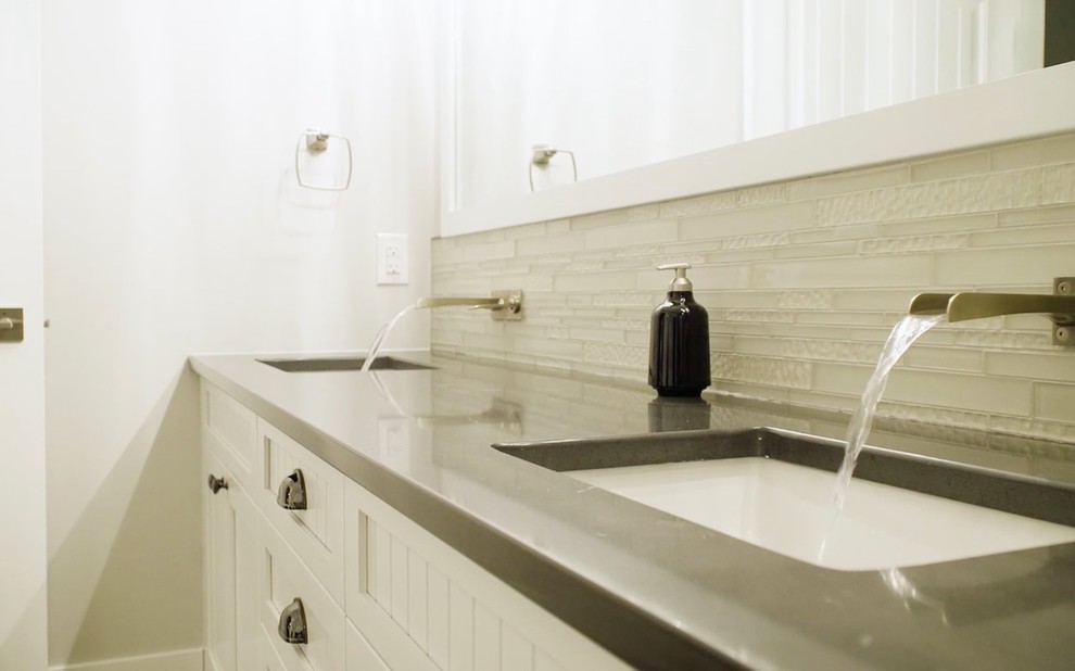 Inredning av ett modernt stort grå grått badrum, med luckor med profilerade fronter, vita skåp, en dusch i en alkov, en toalettstol med separat cisternkåpa, vit kakel, glaskakel, vita väggar, klinkergolv i keramik, ett undermonterad handfat, bänkskiva i kvarts, brunt golv och dusch med gångjärnsdörr