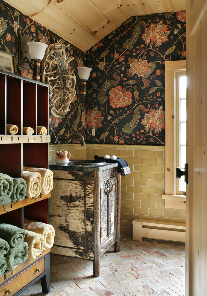 Exemple d'une salle de bain montagne en bois vieilli avec un lavabo posé, un carrelage beige, un carrelage métro, un mur multicolore, un sol en brique et un placard à porte plane.