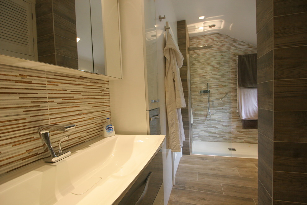 Exempel på ett mellanstort modernt en-suite badrum, med luckor med glaspanel, vita skåp, en kantlös dusch, en vägghängd toalettstol, flerfärgad kakel, porslinskakel, bruna väggar, klinkergolv i porslin och ett väggmonterat handfat