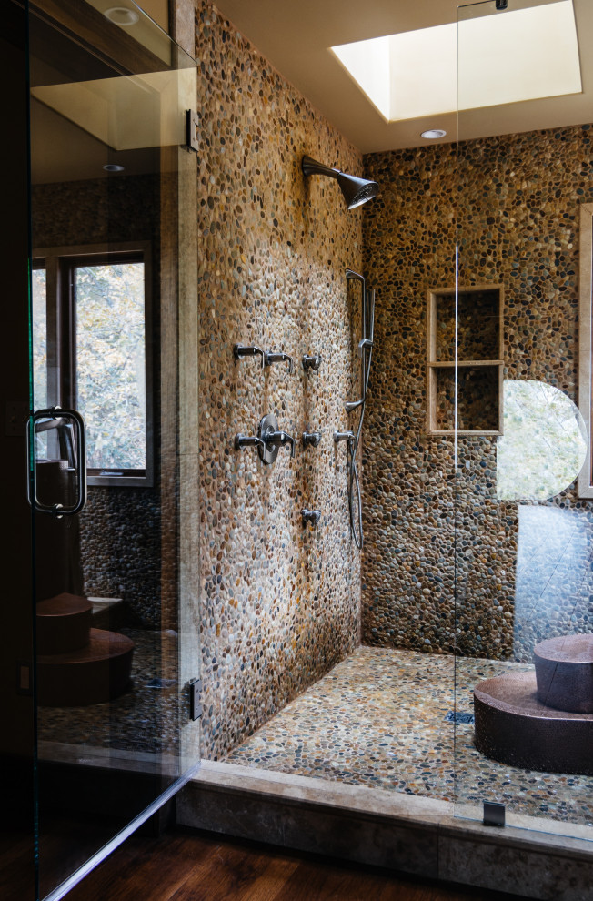 Inredning av ett modernt gul gult en-suite badrum, med möbel-liknande, skåp i mellenmörkt trä, ett japanskt badkar, en dusch/badkar-kombination, en vägghängd toalettstol, grå kakel, kakel i småsten, grå väggar, mellanmörkt trägolv, ett fristående handfat, marmorbänkskiva, brunt golv och dusch med gångjärnsdörr