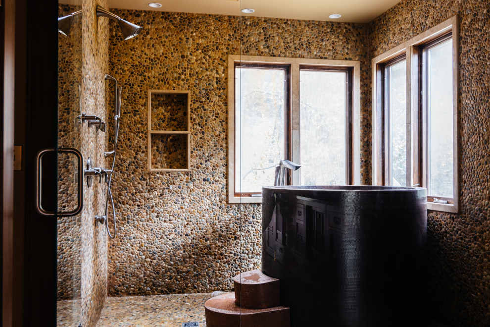 Idéer för funkis gult en-suite badrum, med möbel-liknande, skåp i mellenmörkt trä, ett japanskt badkar, en dusch/badkar-kombination, en vägghängd toalettstol, grå kakel, kakel i småsten, grå väggar, mellanmörkt trägolv, ett fristående handfat, marmorbänkskiva, brunt golv och dusch med gångjärnsdörr
