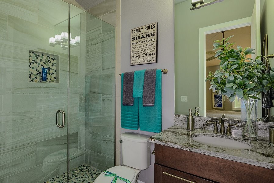 Exempel på ett mellanstort modernt badrum med dusch, med släta luckor, skåp i mörkt trä, en dusch i en alkov, en toalettstol med hel cisternkåpa, grå kakel, grå väggar, ett undermonterad handfat och bänkskiva i kvartsit