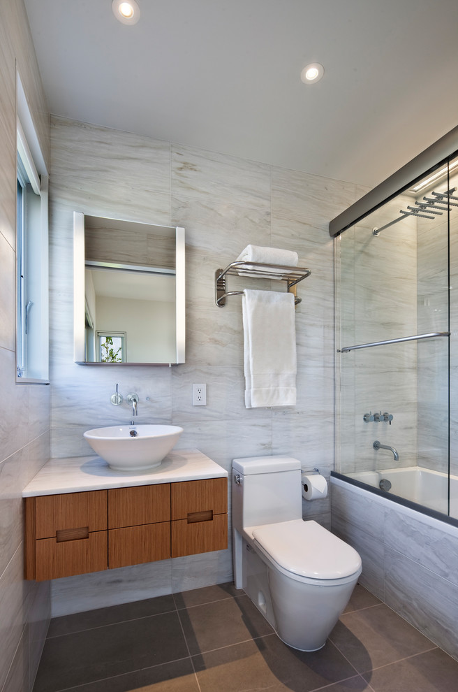 Cette image montre une petite salle de bain principale minimaliste en bois brun avec un placard à porte plane, une baignoire en alcôve, un combiné douche/baignoire, WC à poser, un carrelage blanc, du carrelage en marbre, un mur blanc, un sol en ardoise, une vasque, un plan de toilette en marbre, un sol gris et une cabine de douche à porte coulissante.
