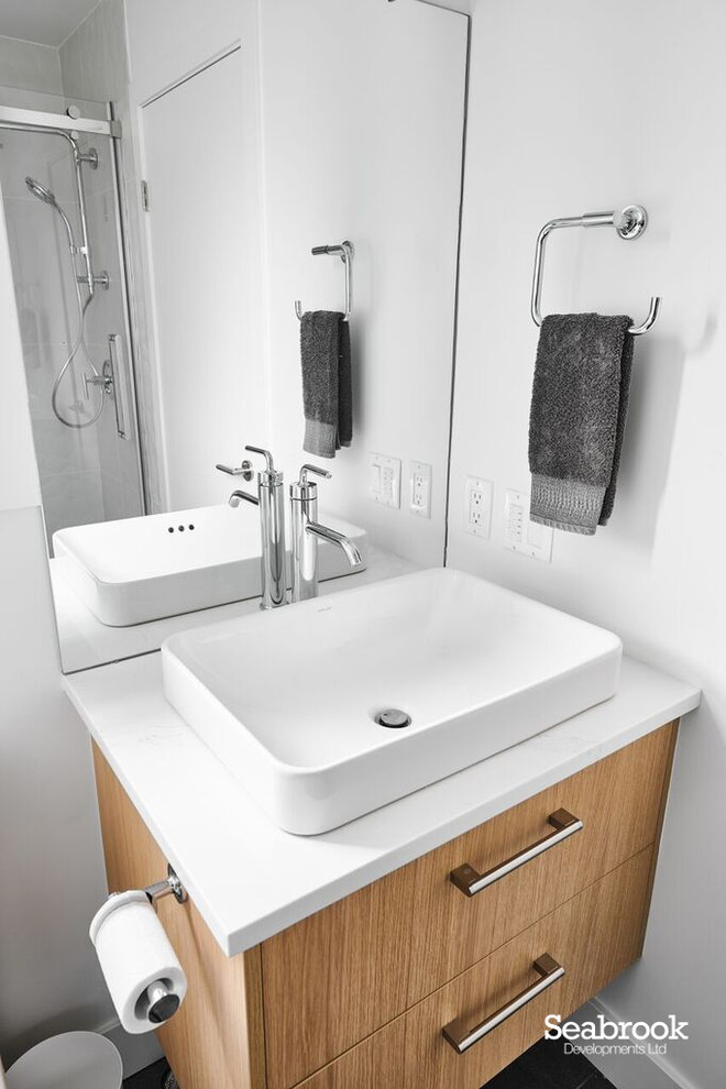 Immagine di una piccola stanza da bagno con doccia contemporanea con ante lisce, ante in legno chiaro, pareti bianche, lavabo a bacinella, top in quarzo composito e top bianco