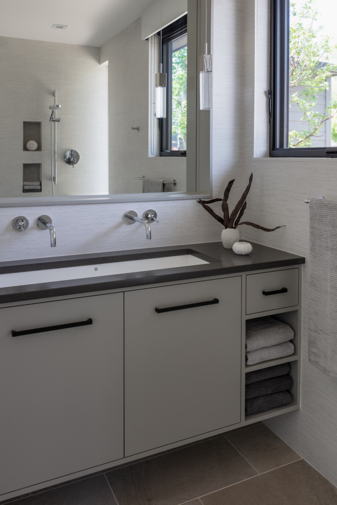 Aménagement d'une salle de bain moderne avec un placard en trompe-l'oeil, une grande vasque et un plan de toilette noir.
