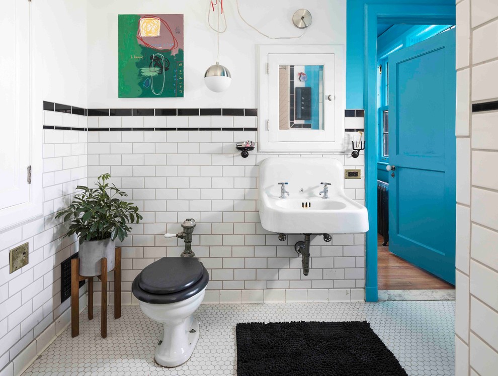 Photo of an eclectic bathroom in Detroit with a one-piece toilet, black tiles, white tiles, metro tiles, white walls, mosaic tile flooring, a wall-mounted sink and white floors.