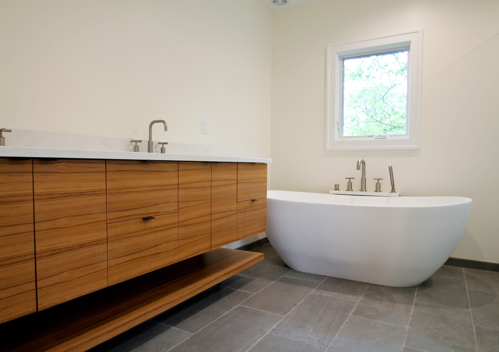 Réalisation d'une salle de bain principale minimaliste en bois brun de taille moyenne avec un placard à porte plane, une baignoire indépendante, WC à poser, un carrelage gris, un mur blanc, un lavabo encastré, un sol gris, un plan de toilette blanc et un sol en ardoise.
