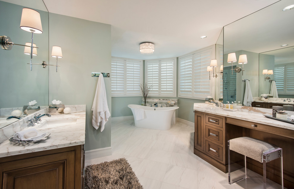 Exemple d'une grande salle de bain principale chic en bois brun avec une baignoire indépendante, un plan de toilette en marbre, un lavabo posé, un placard avec porte à panneau surélevé, un carrelage blanc, des dalles de pierre, un mur bleu et un sol en marbre.