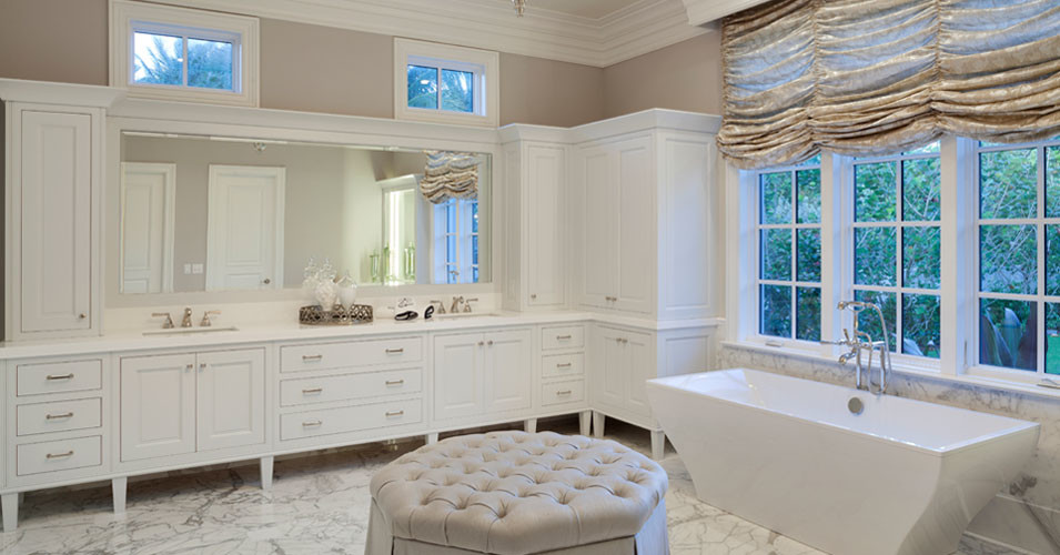 Klassisk inredning av ett stort en-suite badrum, med ett undermonterad handfat, vita skåp, ett fristående badkar och beige väggar