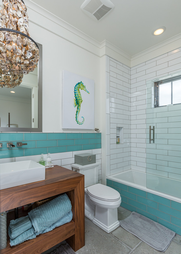This is an example of a medium sized coastal ensuite bathroom in Miami with open cabinets, dark wood cabinets, a corner bath, a shower/bath combination, a one-piece toilet, blue tiles, white tiles, metro tiles, white walls, concrete flooring, a vessel sink and wooden worktops.
