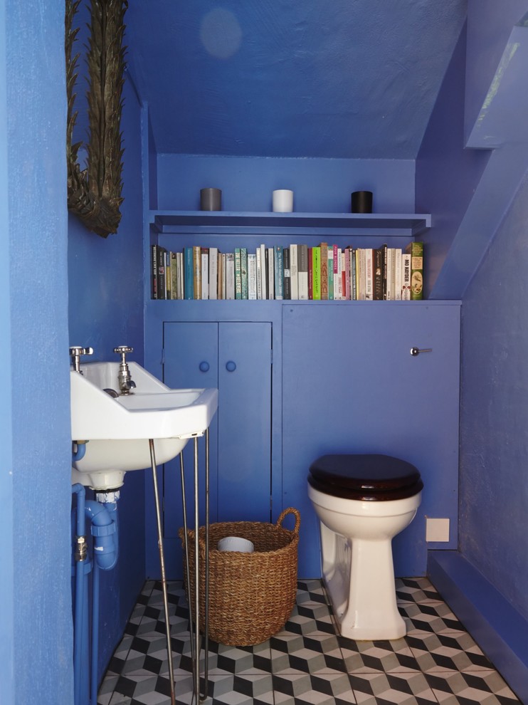 Inspiration för klassiska toaletter, med släta luckor, blå skåp, en toalettstol med separat cisternkåpa, blå väggar, ett konsol handfat och grått golv