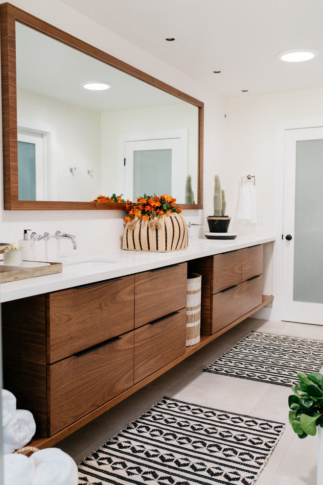 Ejemplo de cuarto de baño blanco y madera actual con armarios con paneles lisos, puertas de armario de madera en tonos medios, paredes beige, lavabo bajoencimera y encimeras blancas