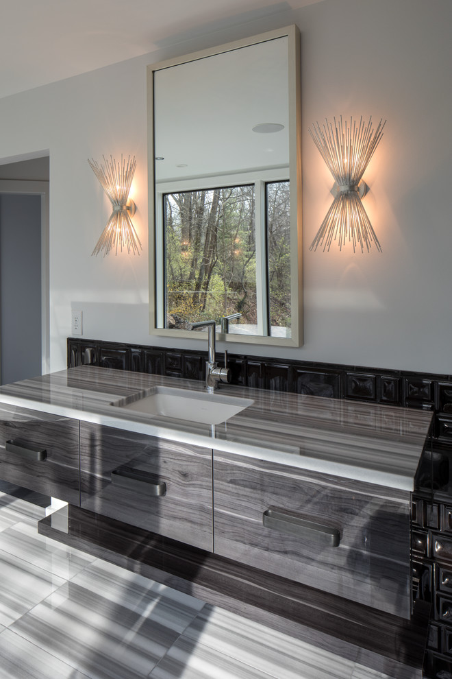 This is an example of an expansive traditional ensuite bathroom in Indianapolis with flat-panel cabinets, black cabinets, a freestanding bath, an alcove shower, a wall mounted toilet, black tiles, ceramic tiles, grey walls, a submerged sink, engineered stone worktops, grey floors and a hinged door.