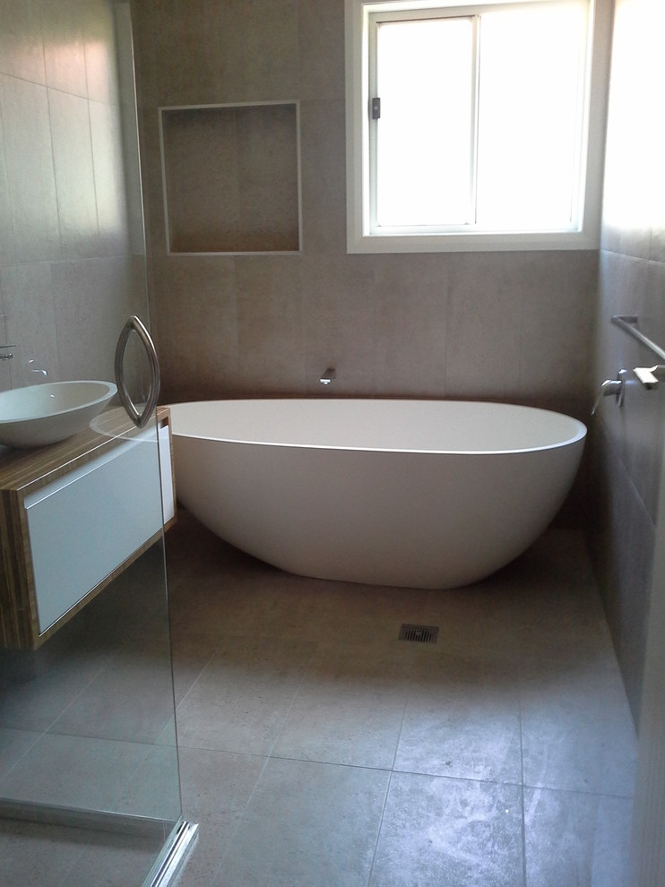 Ejemplo de cuarto de baño principal actual de tamaño medio con bañera exenta, ducha esquinera, baldosas y/o azulejos de cemento y suelo de baldosas de porcelana