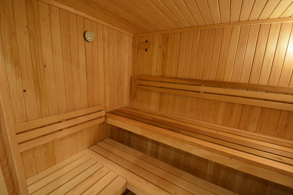 Ejemplo de sauna minimalista grande con armarios tipo vitrina, ducha esquinera, baldosas y/o azulejos negros, paredes amarillas y suelo de madera clara