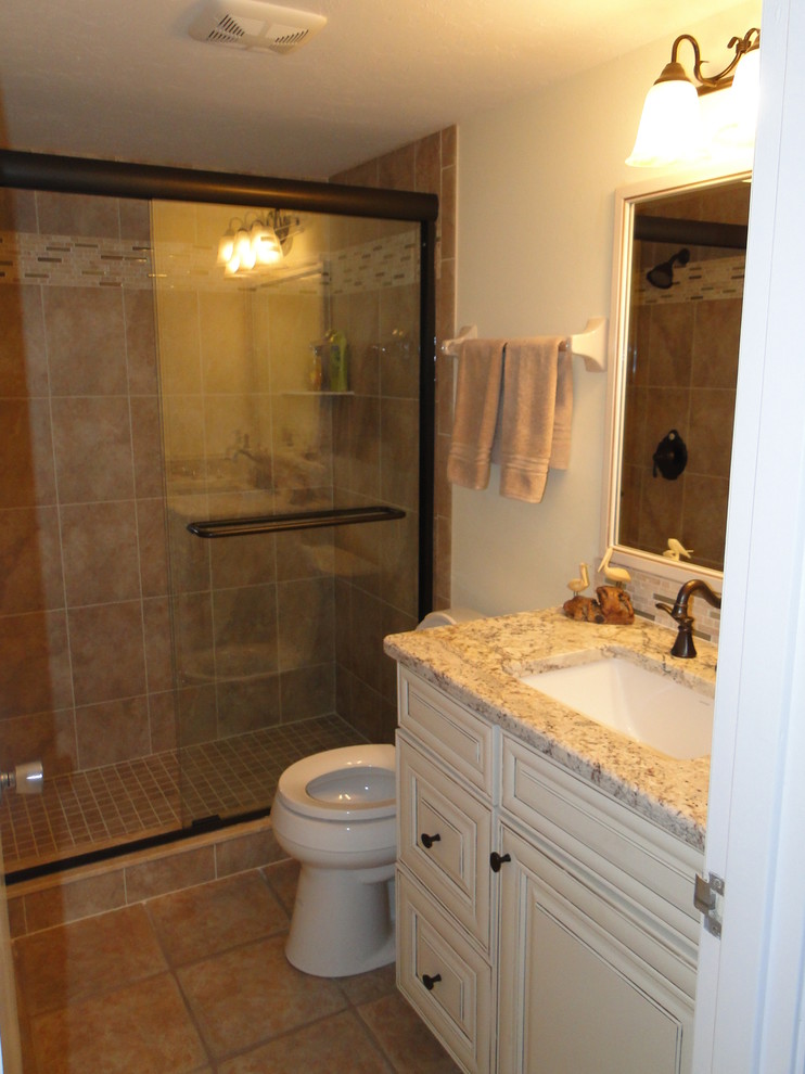 Mid-sized elegant 3/4 brown tile and ceramic tile ceramic tile and brown floor bathroom photo in Tampa with an undermount sink, raised-panel cabinets, white cabinets, granite countertops, a two-piece toilet and white walls