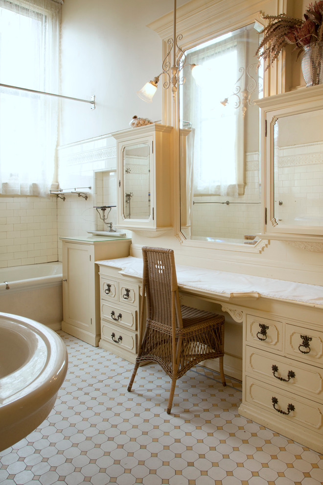 Inredning av ett klassiskt badrum, med beige skåp, ett badkar i en alkov, vit kakel, tunnelbanekakel och beige väggar