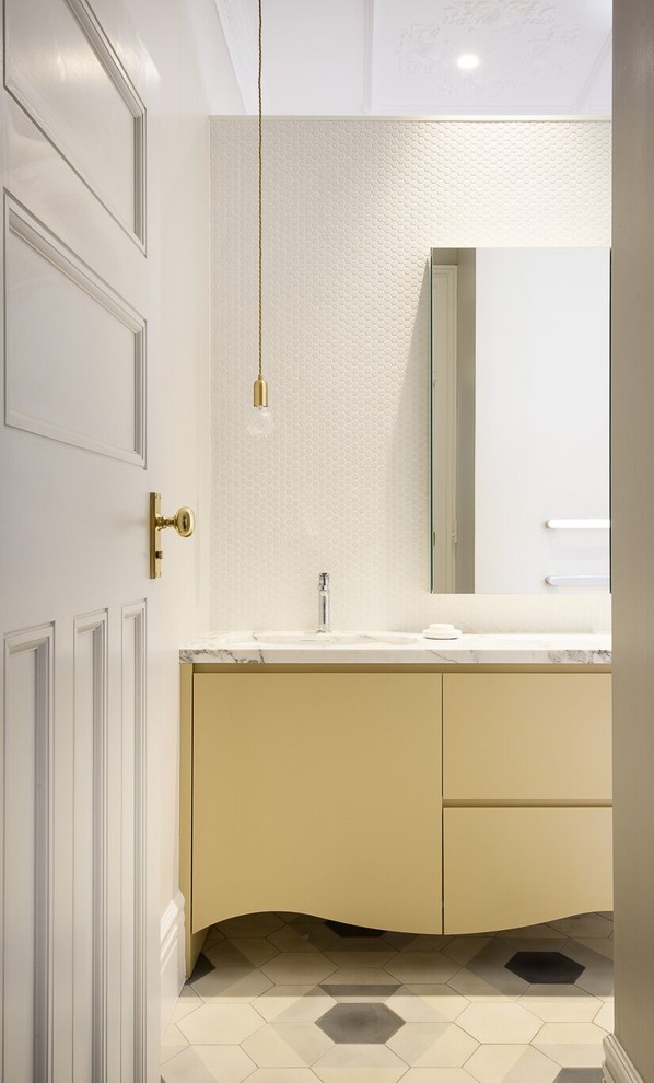 На фото: ванная комната с желтыми фасадами, отдельно стоящей ванной, душем в нише, инсталляцией, белой плиткой, керамической плиткой, серыми стенами, бетонным полом, врезной раковиной и мраморной столешницей с