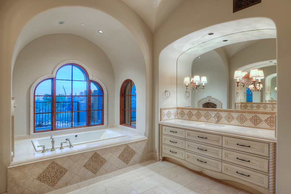 Réalisation d'une très grande salle de bain principale tradition avec un placard en trompe-l'oeil, des portes de placard beiges, une baignoire en alcôve, mosaïque, un lavabo intégré, un plan de toilette en granite, un carrelage blanc, un mur blanc et un sol en travertin.